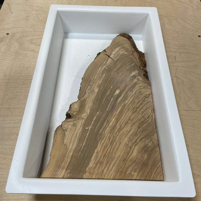 Live edge olive wood board placed inside 10 x 18 HDPE epoxy mold for resin casting