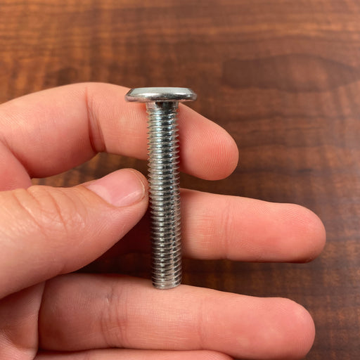 hand holding a long threaded screw with a flat head