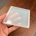 hand holding a small square silicone mold that is perfect to make a coaster with either just resin or wood and epoxy combine