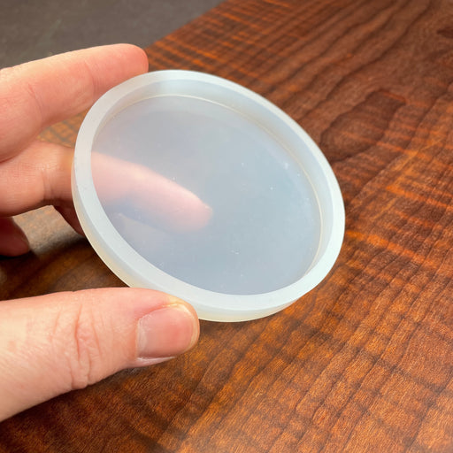 a tiny circle mold that can be reused being held by a hand for scale reference