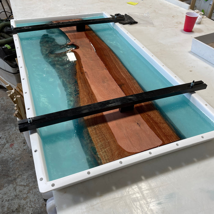big form with two hold down bars going horizontally across the form allowing the curupay wood species to not float up . You can see the turquoise resin on either side of the slab that runs up the middle of the form