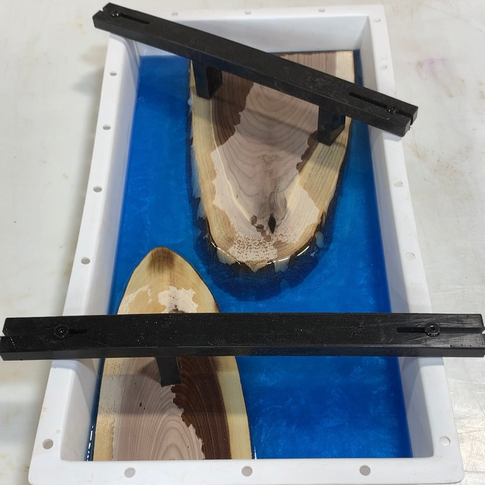 blue resin inside a hdpe form that has two walnut cookies halves being held down by HDPE blocks and bars bolted to the side of the form