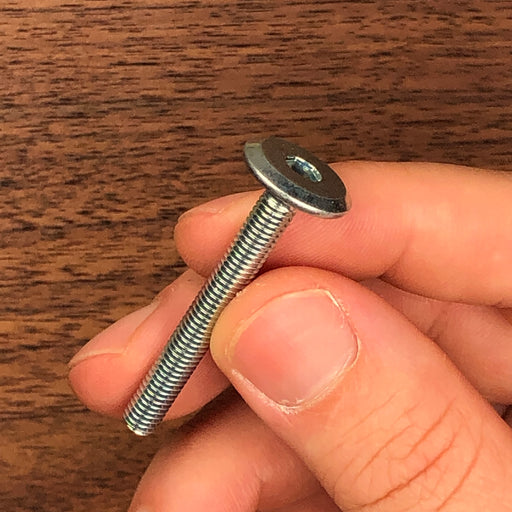 hand holding a threaded screw for scale reference showing the hexagonal top pattern
