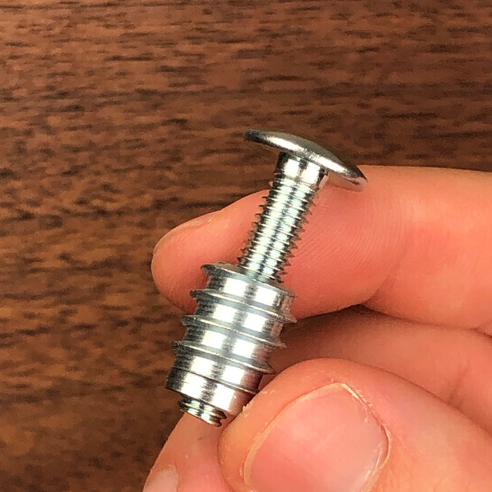 shorter legth of a flat head screw inside a threaded insert being held between two fingers to show scale and size