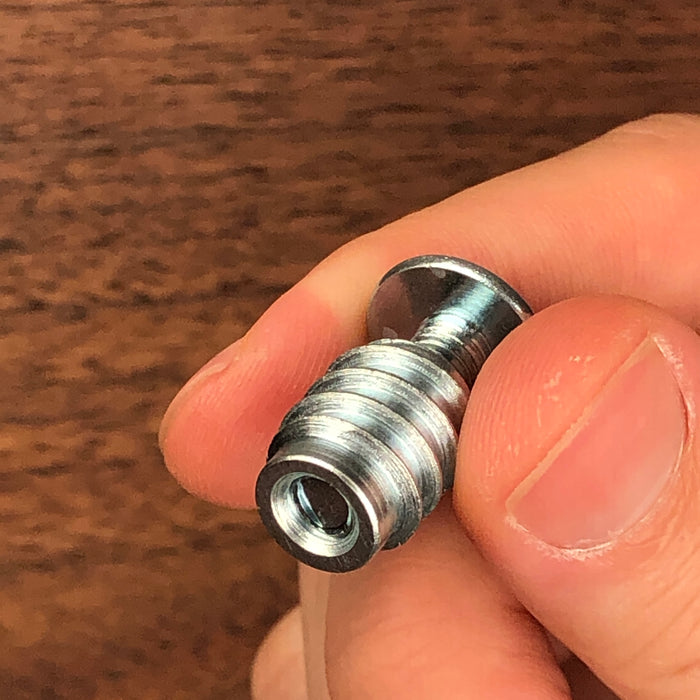 two fingers holding the threaded insert and angled so you can see how the bottom of the bolt does not have to be screwed in the entire way for maximum strength 
