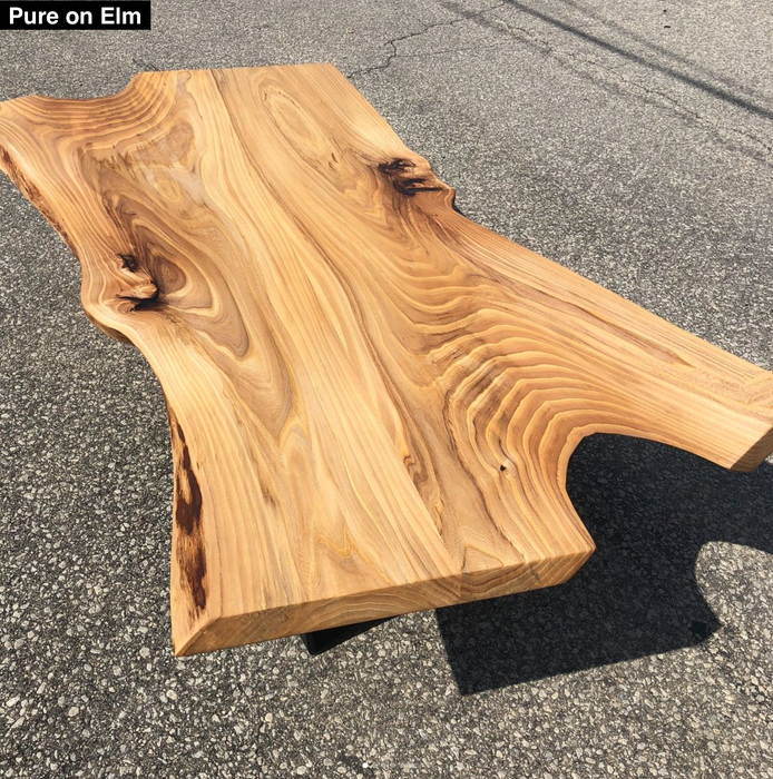 elm coffee table that has a live edge and voids filled with epoxy finished with pure oil finish
